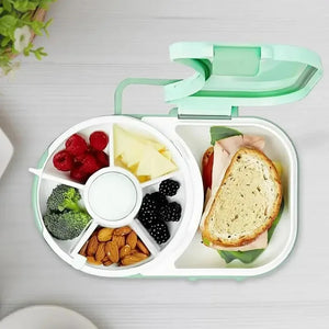 Lunch box with compartments containing a sandwich, fruits, and vegetables on a light background