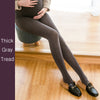 Person wearing thick gray tights sitting on a wooden floor.