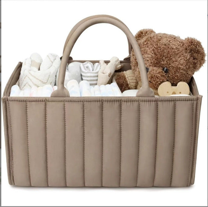 Beige baby caddy with baby items including a teddy bear on a white background