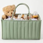 Green baby caddy with teddy bear, diapers, and other items on a white background