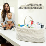 Woman holding a baby and a teddy bear next to a white woven basket filled with items on a table.