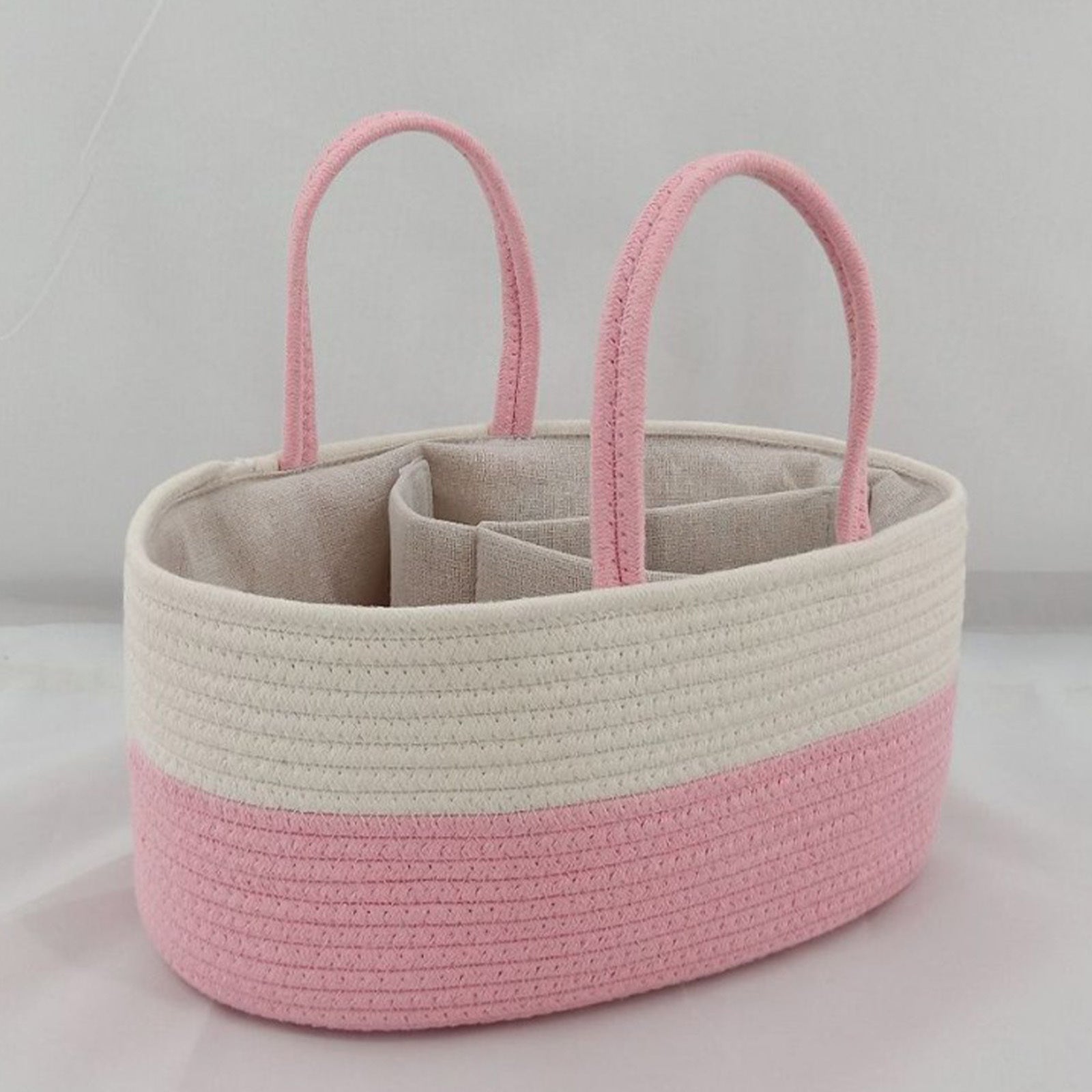 Pink and beige woven basket with handles on a light gray background