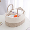 Beige woven basket with handles containing baby items on a white surface.