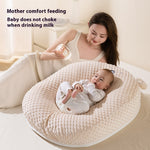 Woman feeding a baby with a bottle on a textured cushion