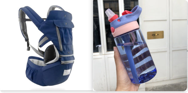Navy baby carrier and blue water bottle with pink lid held by a hand.