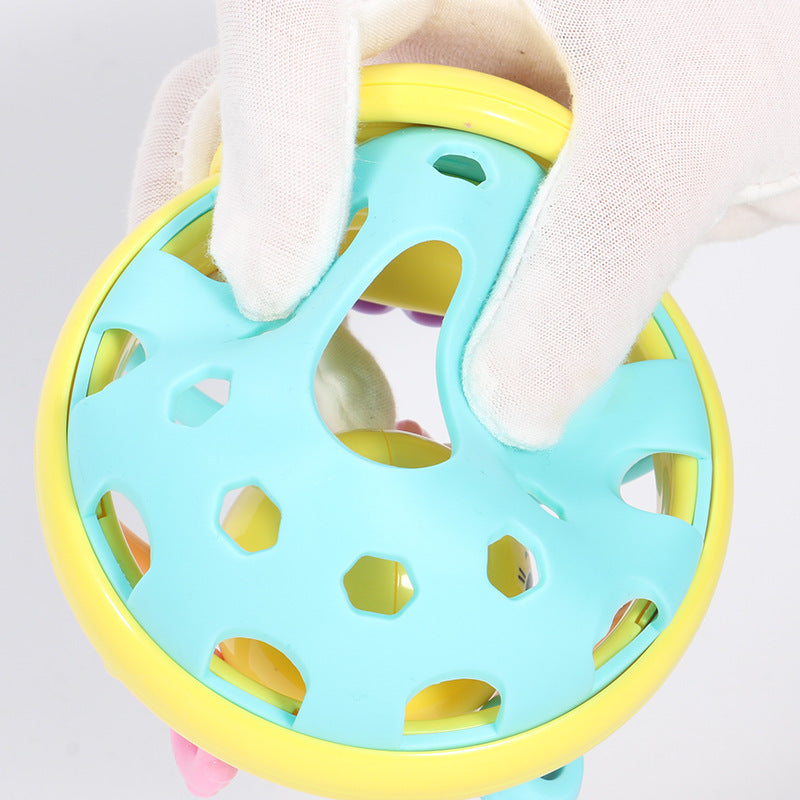 Colorful baby teething ring held by a gloved hand against a light background