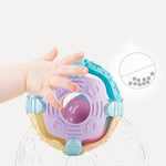 Colorful baby teething ring with a hand reaching towards it on a light gray background