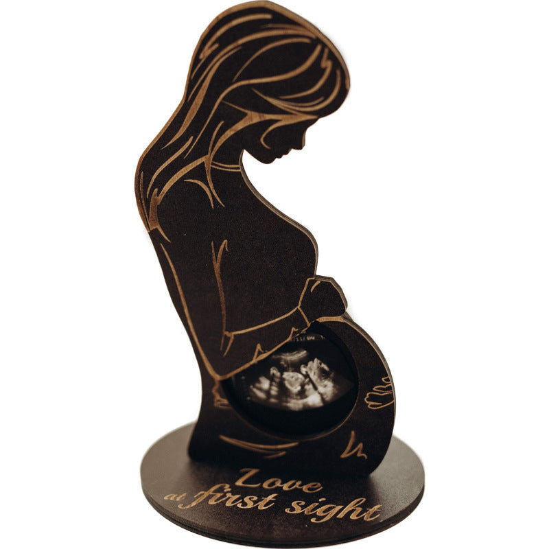 Decorative stand with silhouette of a pregnant woman and ultrasound, featuring the text 'Love at first sight'.