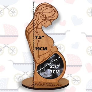 Wooden sculpture of a pregnant woman with an ultrasound inside, showing measurements and text.