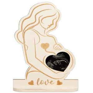 Wooden ornament of a pregnant woman holding a heart-shaped frame with 'love' engraving on a white background.