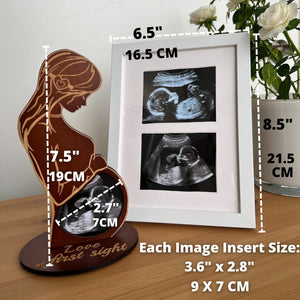 Wooden sculpture of a pregnant woman with ultrasound images and measurements on a table.