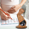 Wooden figurine of a pregnant woman with an ultrasound inside, next to a calendar and a hand holding a pen.