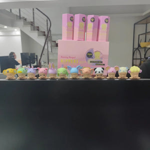 Row of colorful plush toys in front of pink boxes on a black surface.