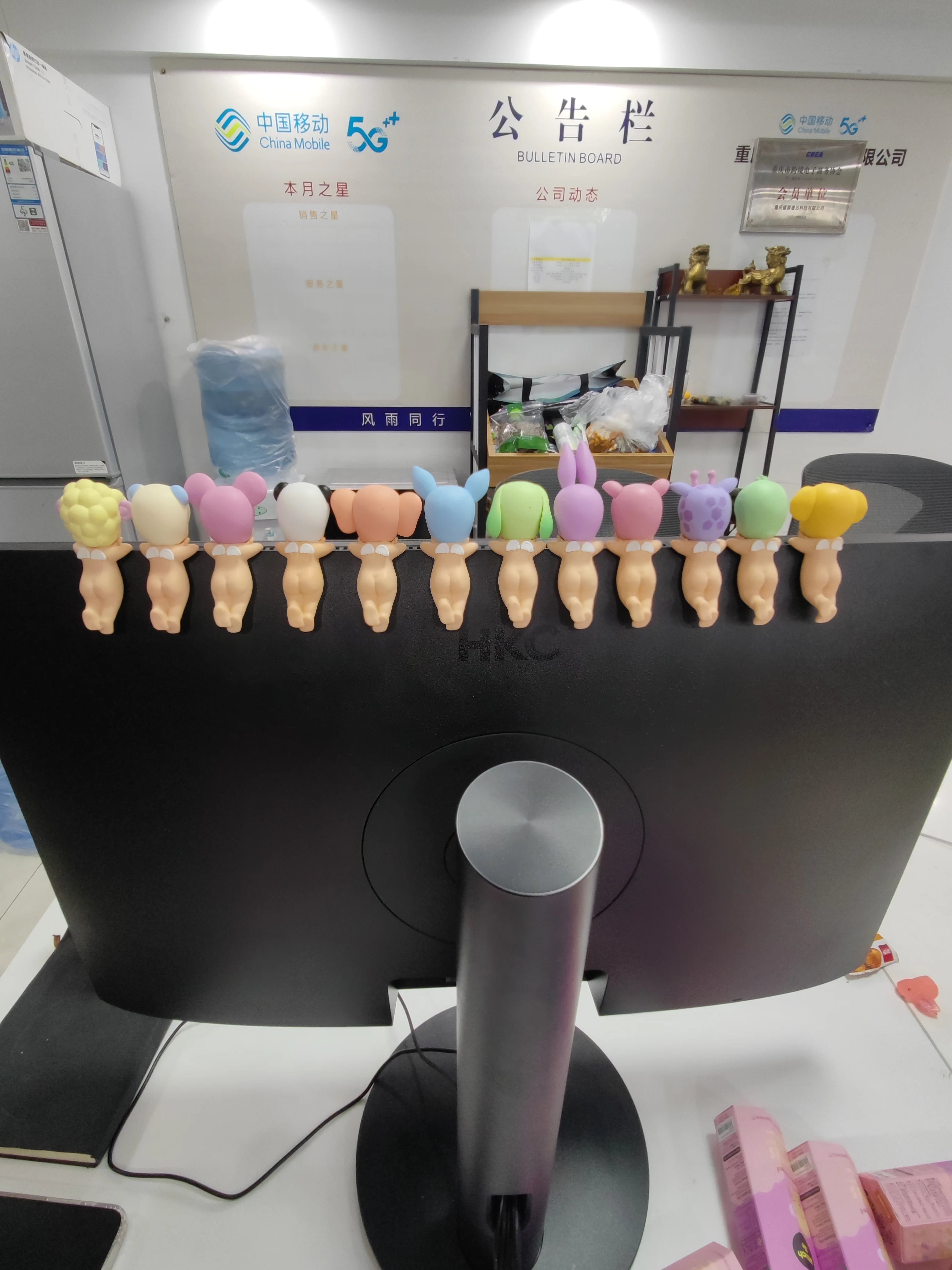 Computer monitor with colorful bear-shaped desk organizers in an office setting