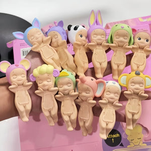 Set of baby figurines with various hairstyles and accessories on a pink surface.