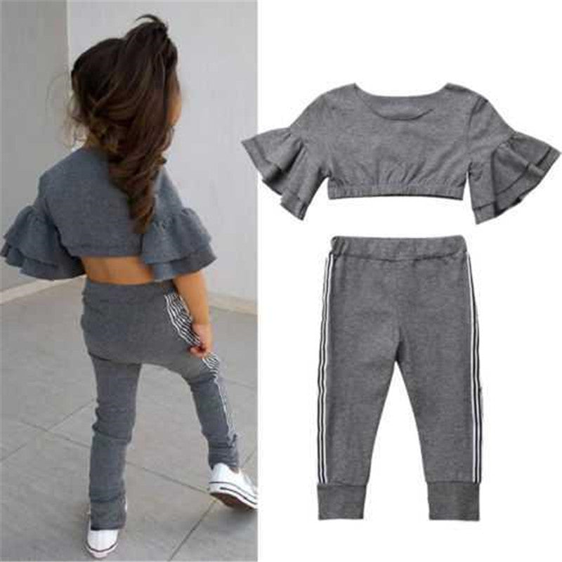 Gray ruffled top and pants set with a child wearing it on a light gray background
