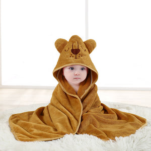 Baby wrapped in a brown bear hooded towel on a white surface