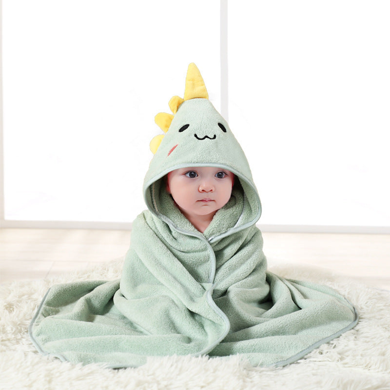 Baby wrapped in a green hooded towel with a cartoon dinosaur design on a white background