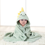 Baby wrapped in a green hooded towel with a cartoon dinosaur design on a white background