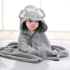 Child wearing a gray elephant hooded towel on a bed