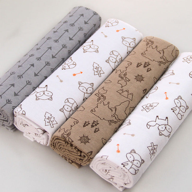 Four folded fabric swatches with animal and nature patterns on a light background