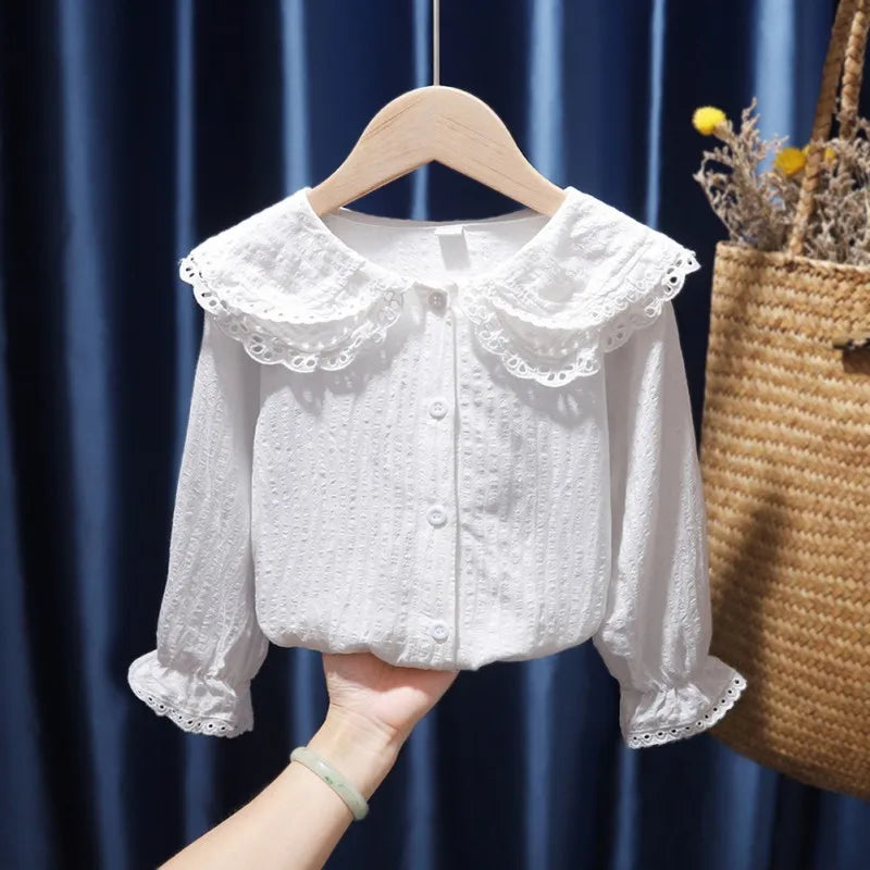 White lace blouse on a hanger against a blue curtain background