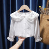 White lace blouse on a hanger against a blue curtain background