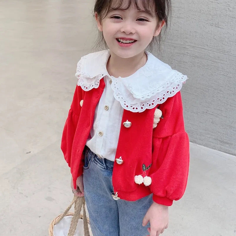 Child wearing a red jacket with white lace details on a neutral background