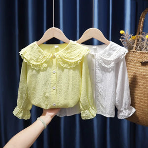 Yellow and white lace blouses on hangers against a dark blue curtain background.