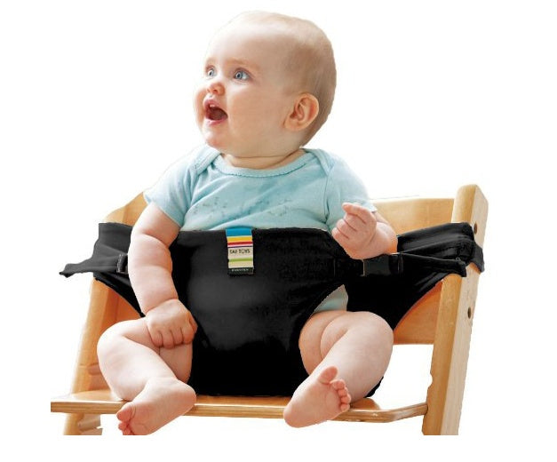 Baby sitting on a wooden chair with a black seat cover