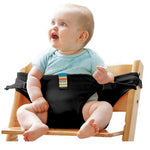 Baby sitting on a wooden chair with a black seat cover