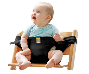 Baby sitting on a wooden chair with a black seat cover