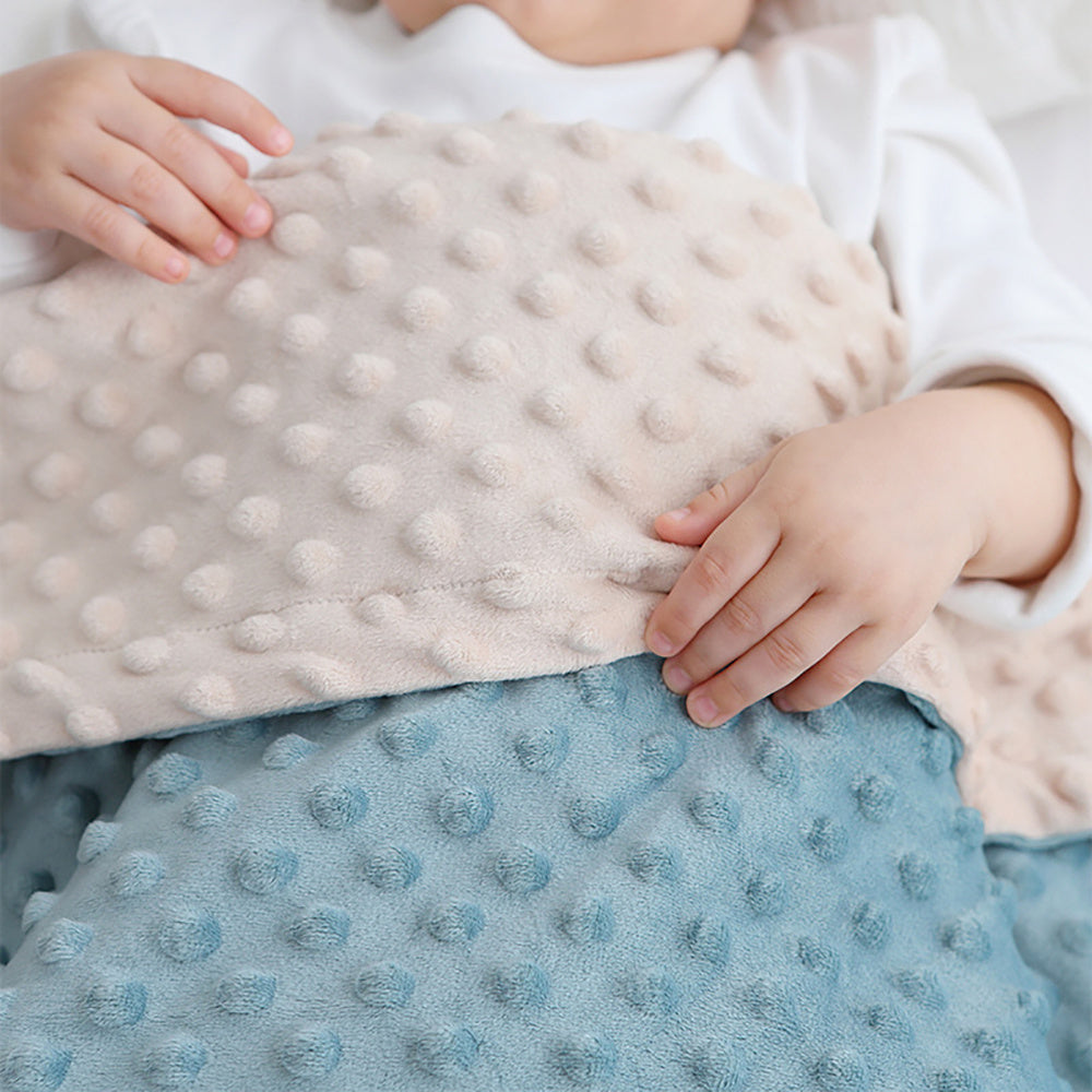 Child holding a textured blanket with soft fabric