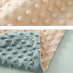 Two textured blankets, one beige and one light blue, on a light gray background.