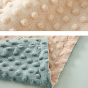 Two textured blankets, one beige and one light blue, on a light gray background.