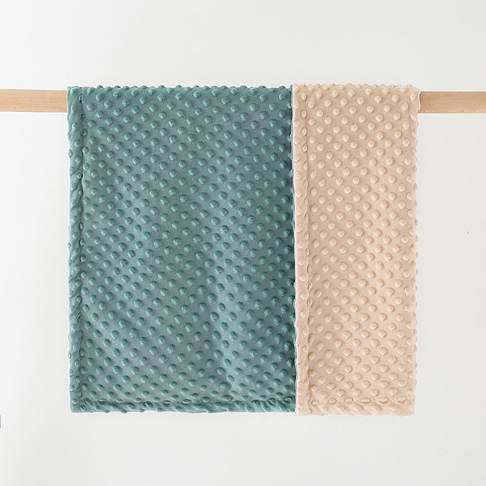 Two textured towels, one green and one beige, hanging on a wooden rod against a white background.