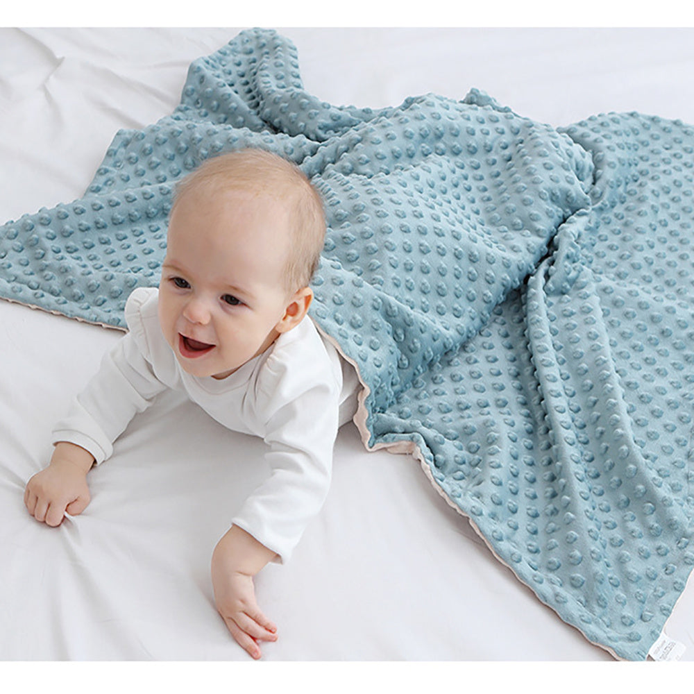 Baby lying on a white surface with a blue textured blanket