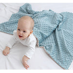 Baby lying on a white surface with a blue textured blanket