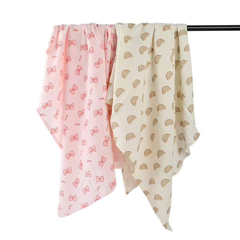 Two baby blankets with pink bow pattern and beige rainbow pattern on a black rod.