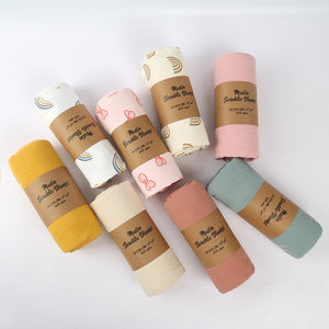 Set of rolled-up blankets in various colors with branded labels on a white background