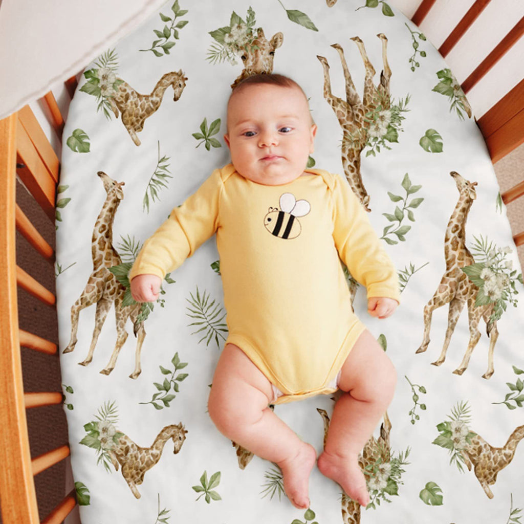 Baby in a yellow onesie with a bee design lying on a crib mattress with giraffe and leaf pattern.
