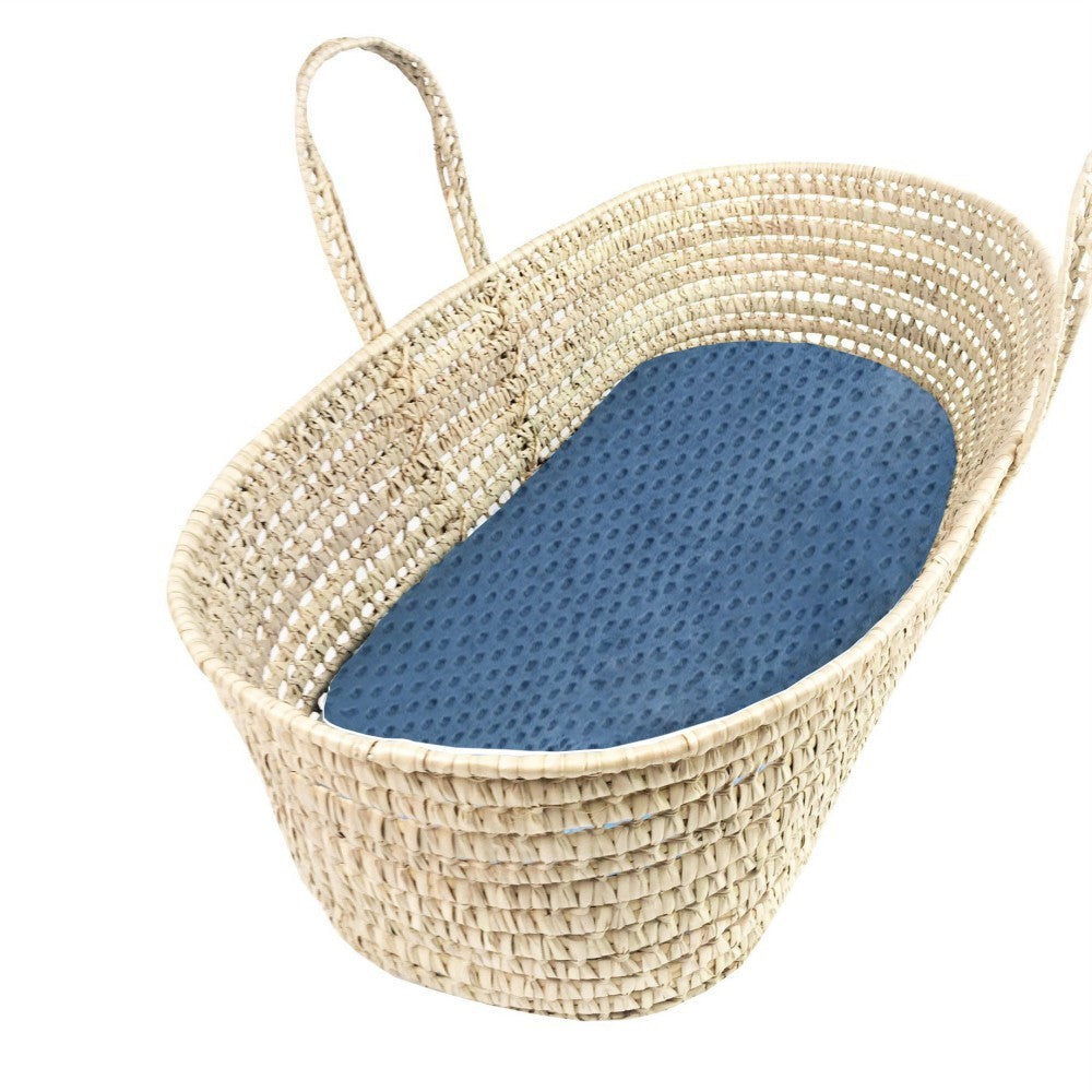 Woven baby crib with blue cushion on a white background
