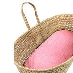 Woven basket with a pink cushion on a white background