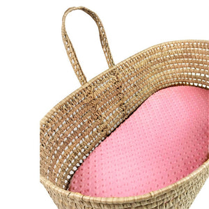 Woven basket with a pink cushion on a white background
