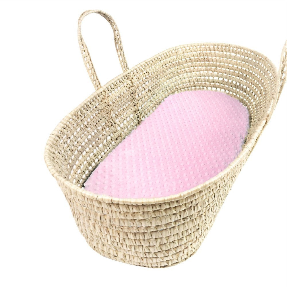Woven baby basket with a pink blanket inside on a white background