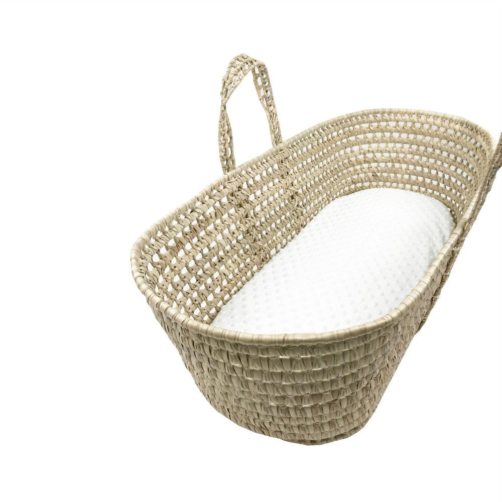 Woven baby Moses basket with a white cushion on a white background