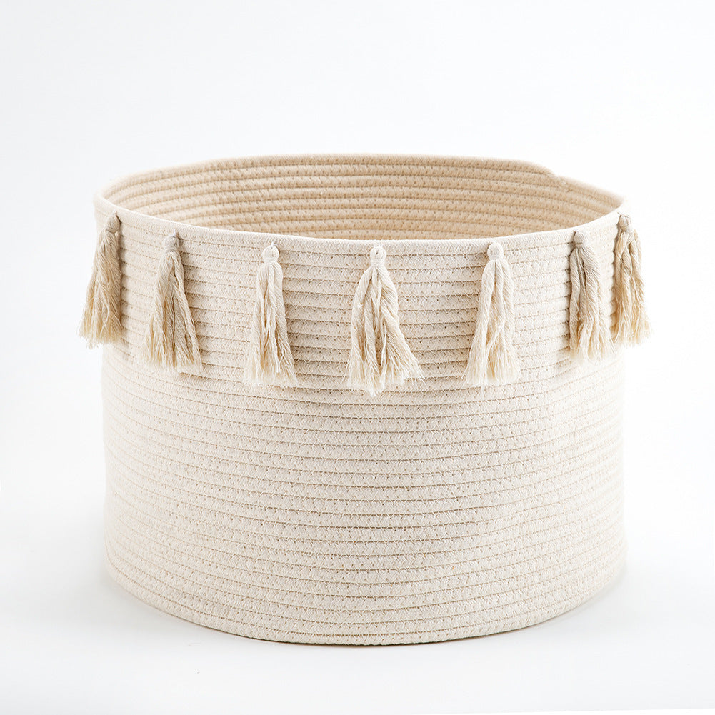 Beige woven basket with tassels on a white background