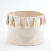 Beige woven basket with tassels on a white background