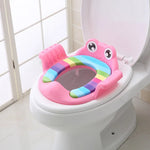 Pink children's toilet seat with rainbow design on a white toilet.