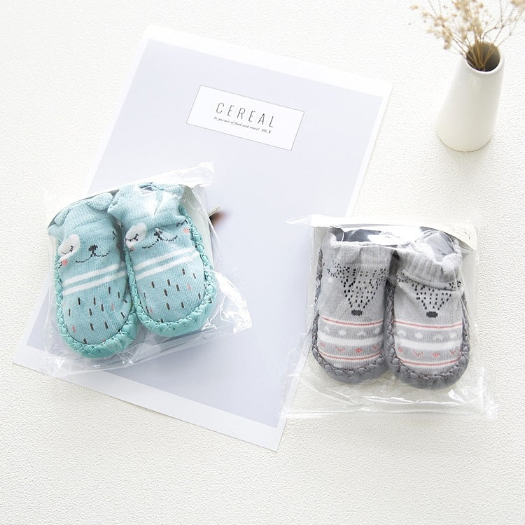 Two sets of baby socks in clear packaging on a white surface with a 'Cereal' box in the background.